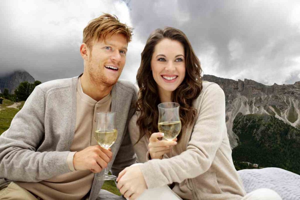 coppia beve vino e sullo sfondo le montagne del trentino