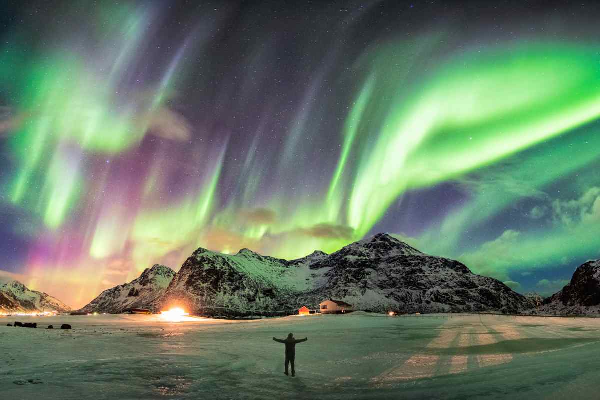 uomo davanti all'aurora boreale in islanda
