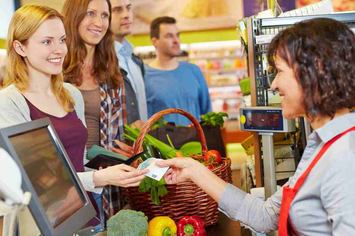 ragazza paga la spesa al supermercato